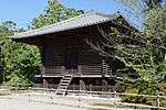 Small and dark wooden building with raised floor on poles.