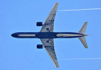 Aircraft in flight, underside view. The jet's two wings have one engine each. The rounded nose leads to a straight body section, which tapers at the tail section with its two rear fins.