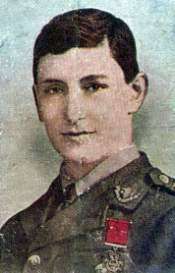 Head and shoulders of a young British officer. He is Caucasian with brown hair that is parted to the right. He is wearing a military uniform with the Victoria Cross pinned to the left breast.