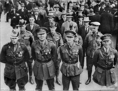 Lines of men in rows of four wearing military uniforms or suits and military medals.