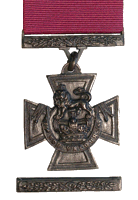 A bronze cross pattée bearing the crown of Saint Edward surmounted by a lion with the inscription FOR VALOUR. A crimson ribbon is attached