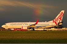 A medium jetliner with an all-white body, red wingtips and a Virgin logo on the tail.