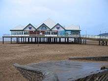 Building on stilts above sand.