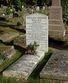 A white marble headstone surrounded by many other gravestones