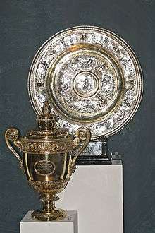 A golden trophy, in the shape of a loving-cup, next to a silver plate