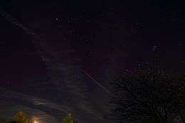 photograph of night sky above a dimply-lit horizon