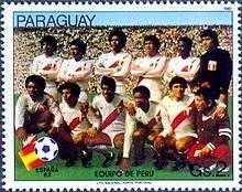 Twelve men, six standing and six crouching, pose for a photo inside a stadium