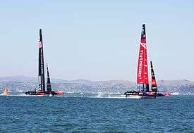 Color photograph of a racing catamaran underway with the starboard hull out of the water