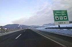 Motorway approaching the Ravna Gora rest area; a directional traffic sign specifying some rest area amenities is visible on the right side of the road.