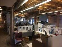 An office space with cubicles and exposed brick walls