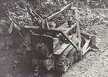 A bulldozer clears a path through the jungle