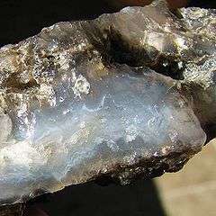 A chunk of seam agate with the split face showing fortification banding in gray, blue and white colors.