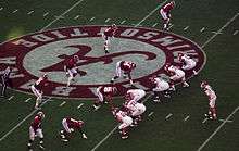 American football players in formation waiting for the snap at midfield.