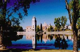 Stone church or monastery complex beyond a lake.