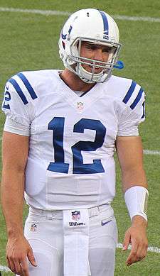 A man wearing a red jersey with the number 12 on it while sitting down.