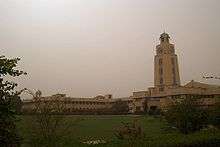 Low, gold-colored building seen from green space