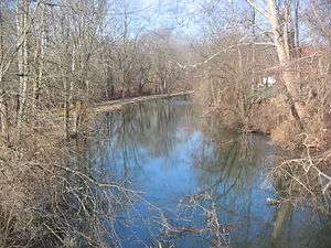 Leafless trees overhang a water channel that is uniformly about 25 feet (8 meters) wide.