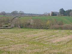 A few buildings scattered amongst fields and trees.