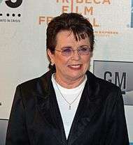 A brown haired women in a black jacket and white shirt