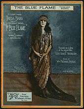 Sheet music cover showing a white woman with long, dark hair, dressed in a floor-length patterned gown and matching headpiece; her image is surrounded by text giving credits for the play and song