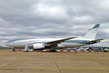 twin-engine jet airliner on ground with boarding stairs connected.