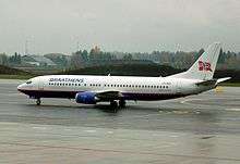 A medium-sized passenger jet on a tarmac with a white top and tail, and a blue bottom. There is a Norwegian flag on the tail and "Braathens" written along the side"