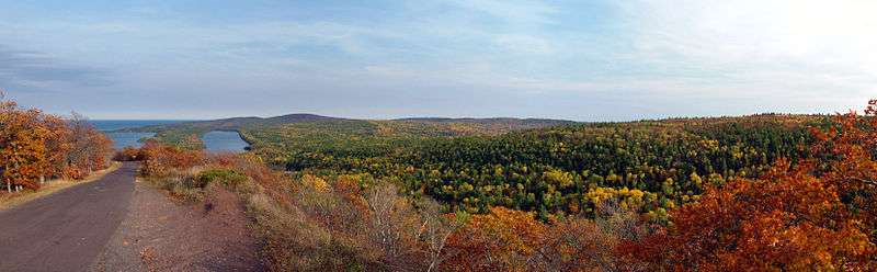 An autumnal panorama from the top of Brockway Mountain with Lake Fanny Hooe and Lake Superior in the distance and Brockway Mountain Drive descending the hill