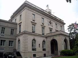 A three-story gray mansion, with an impressive covered front entrance