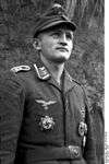 A man wearing a military uniform, field cap and various military decorations.