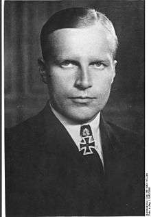 Black-and-white portrait of a man wearing a military uniform, white shirt with an Iron Cross displayed at his neck.