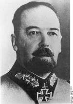 A black-and-white photograph of a bearded man wearing a military uniform, with an Iron Cross at his neck.