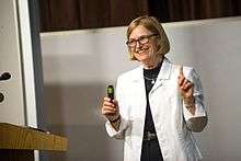 Hickson speaking, next to a podium, at the University of the Fraser Valley