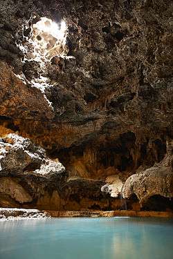 Interior of the Cave at Cave and Basin National Historic Site in Banff, Alberta, Canada, showing an overhead opening, small waterfall, and pool of water