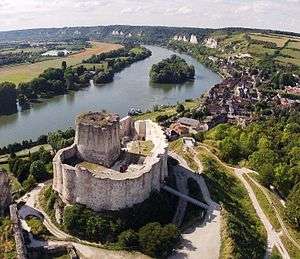 The ruins of a castle in grey limestone. It dominates the landscape.