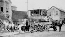 An African-American family moves out of a house with broken windows.