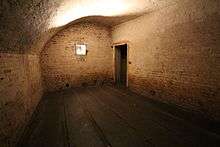 View of a cartridge magazine in the fort, an empty room with an arched ceiling and grooved wooden battens covering the floor