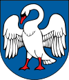 A coat of arms depicting a white bird with wings outspread, a red beak, and red feet all on a dark blue background