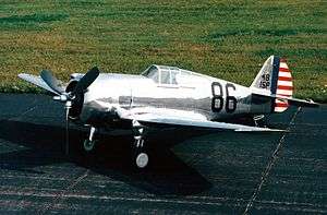 Shiny metal single-engine propeller-driven aircraft on a tarmac.