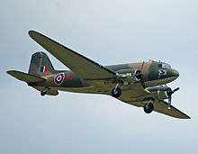 A camouflaged military plane is viewed from the right and from slightly below. British Royal Air Force markings are prominent.