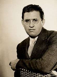 head shot of a well-dressed man wearing glasses