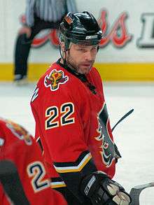 Hockey player in red uniform. He has turned his face toward the camera.