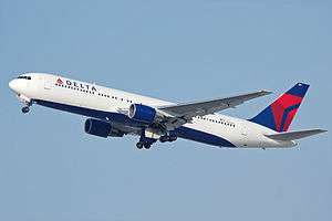 A side/underneath view of a Boeing 767-300 in Delta Air Lines' white, blue and red color during climbout.  The main undercarriage doors are retracting.