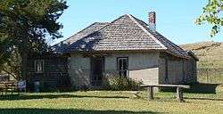 Small house with steep-pitched roof; single brick chimney