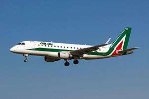 A white, green and red Embraer E175 aircraft in landing configuration.