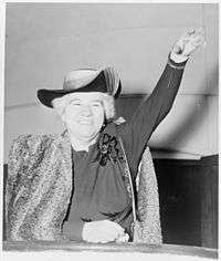 Photo of Elizabeth Kenny 1950, with short white hair, smiling and waving