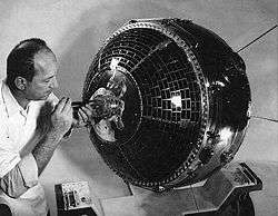 Scientist working on satellite using a tool on the presumed front of the craft