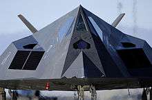 Closeup view of the nose of a black jet, emphasizing the many angled-surfaces