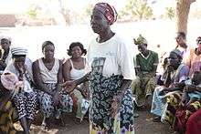 Traditional midwife in Africa at a community meeting, explaining the dangers of cutting for childbirth