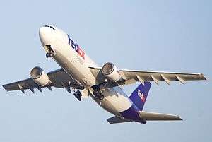 A FedEx Airbus A300 with condensation in both intakes, with its gear retracting.