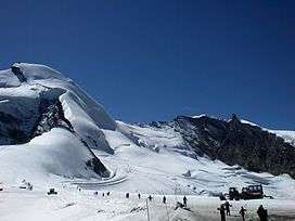 A view of mountain slopes, heavily laden with snow.